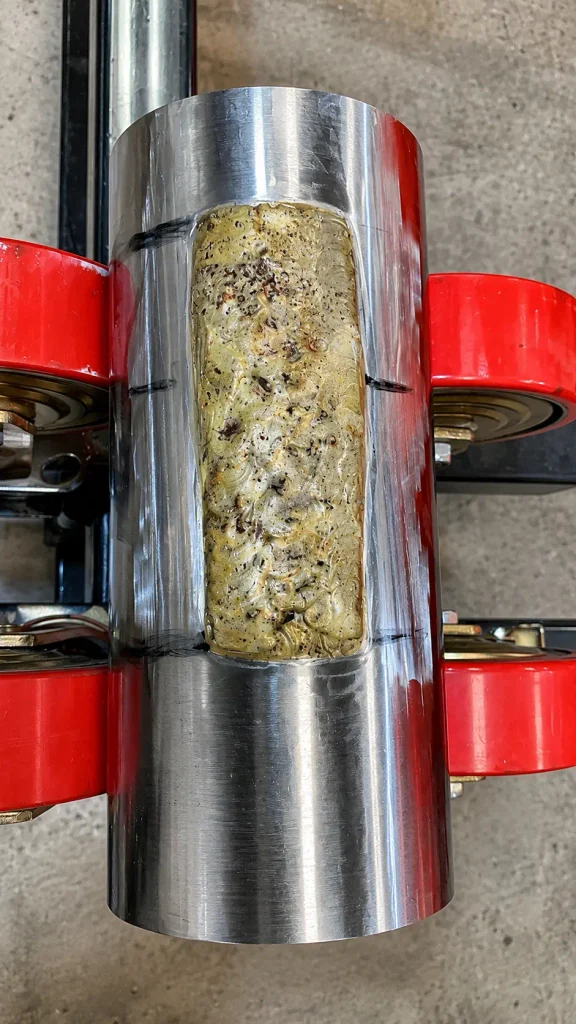 Close-up of crushed tungsten carbide hardfacing deposit on steel sleeve - Accurate Edge UAE